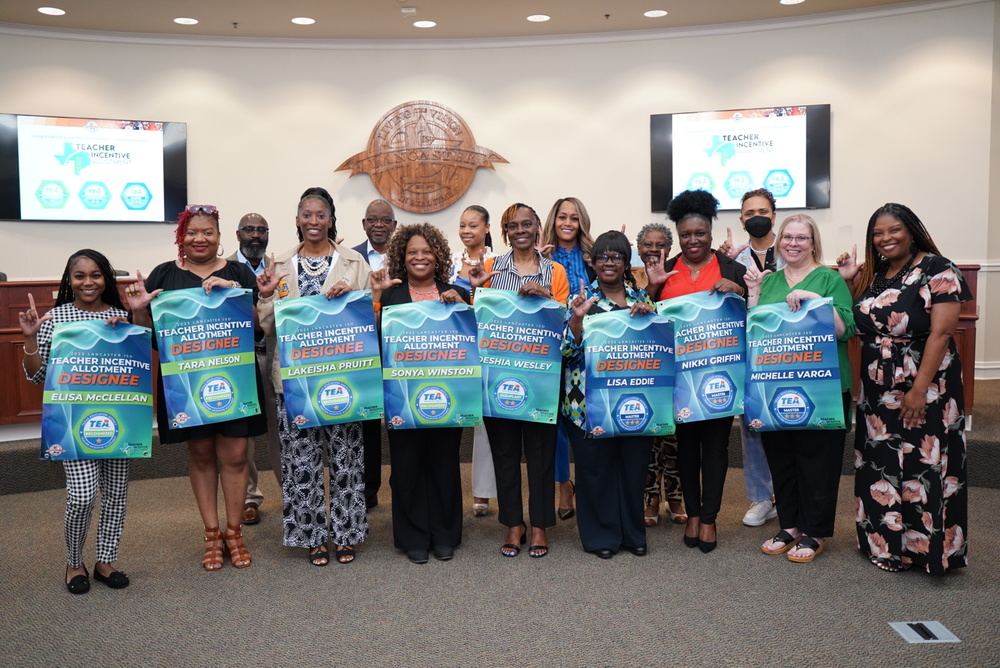 Teachers pose with designation banners